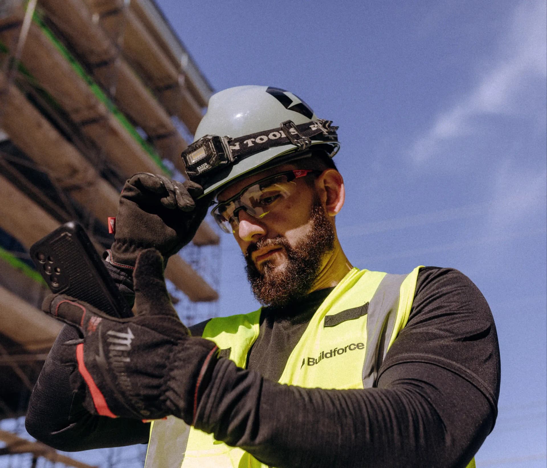 Buildforce worker looking at phone on a construction site.